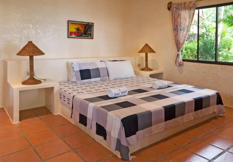 Une chambre lumineuse avec un grand lit recouvert d'une couverture à carreaux.