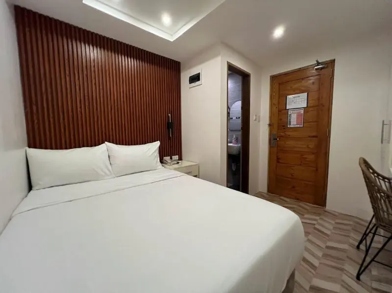 Une chambre lumineuse avec un grand lit et un mur en bois.