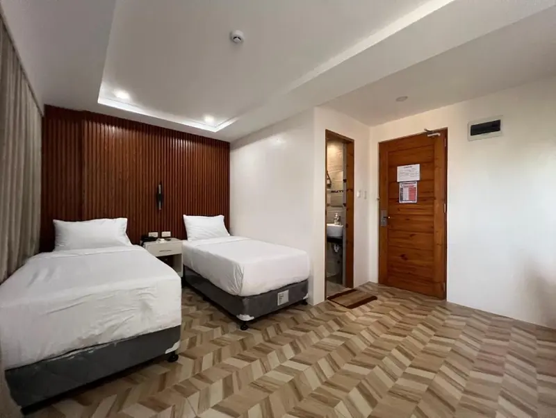Chambre avec deux lits simples et un mur en bois texturé.