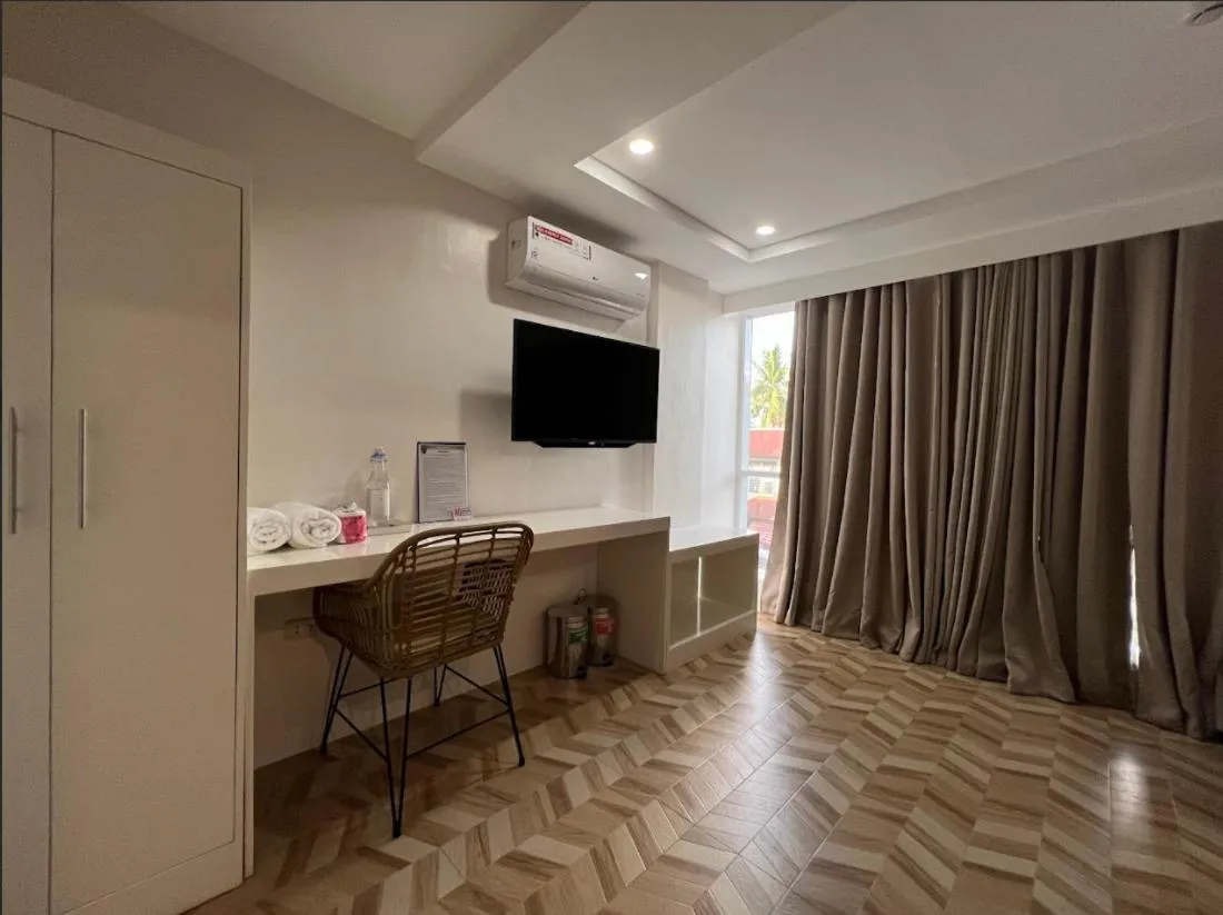 Une pièce lumineuse avec un bureau, une télévision et un accès à une fenêtre.