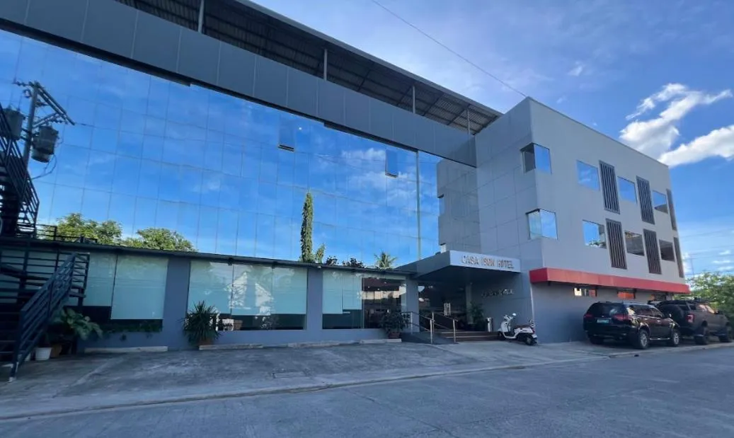 Façade moderne d'un bâtiment avec de grandes baies vitrées et un parking devant.