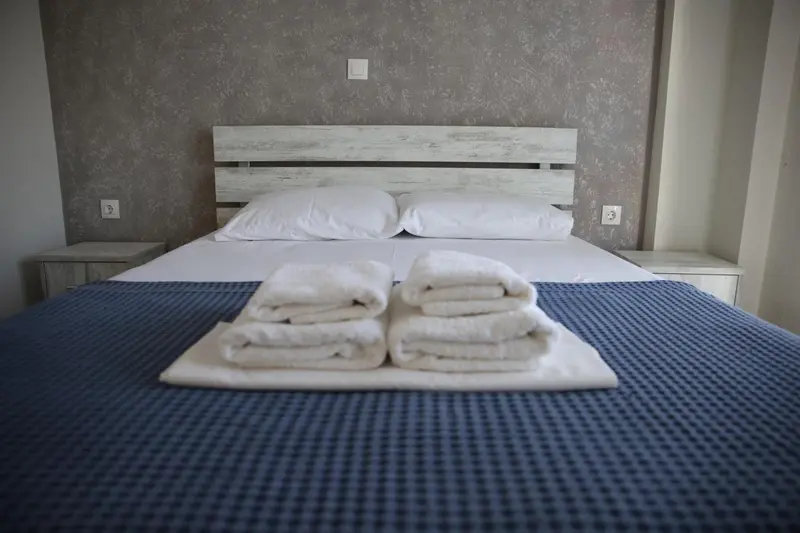Un lit double est recouvert d'une couverture bleue et de serviettes pliées.