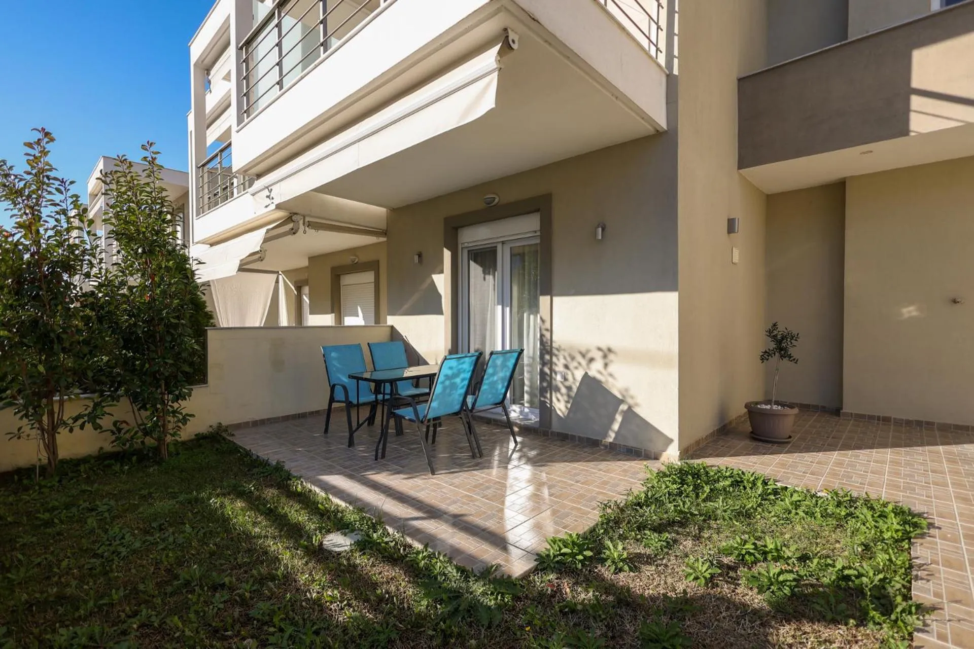 Terrasse avec mobilier de jardin devant un bâtiment beige.
