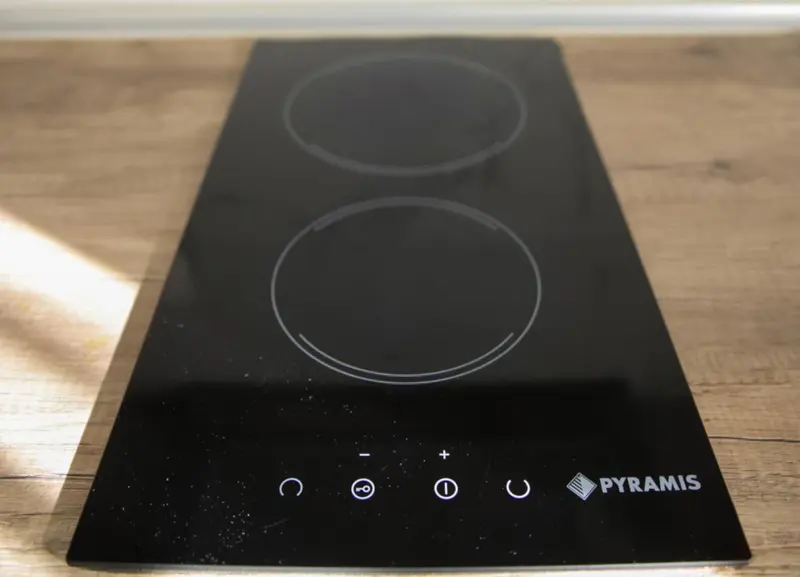 Plaque de cuisson vitrocéramique noire avec commandes tactiles.