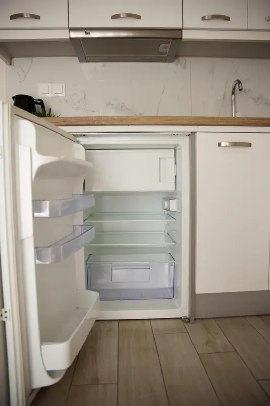 Une cuisine moderne avec un réfrigérateur ouvert et des placards blancs.