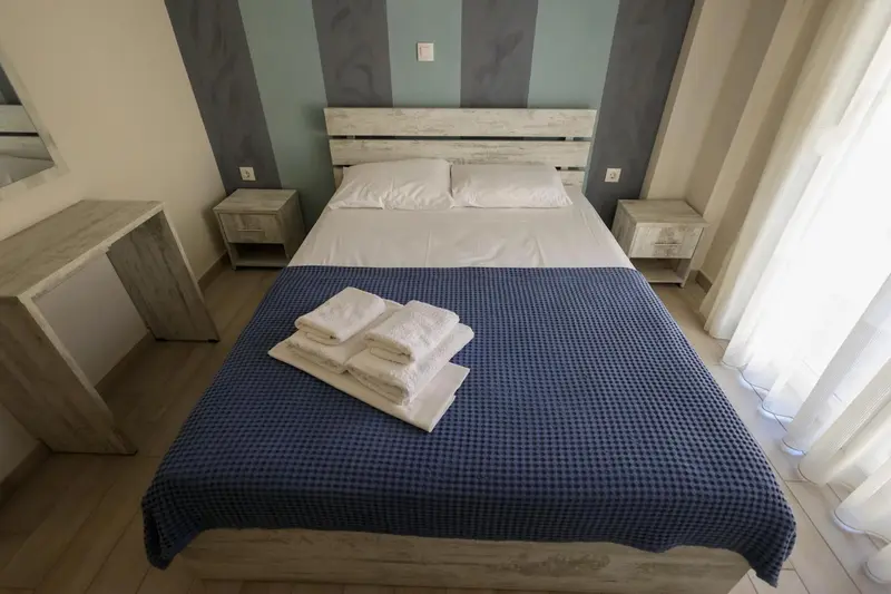 Une chambre lumineuse avec un grand lit recouvert d'une couverture bleue.