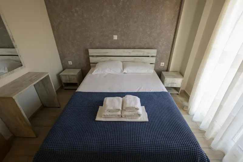 Une chambre lumineuse avec un grand lit recouvert d'une courtepointe bleue.