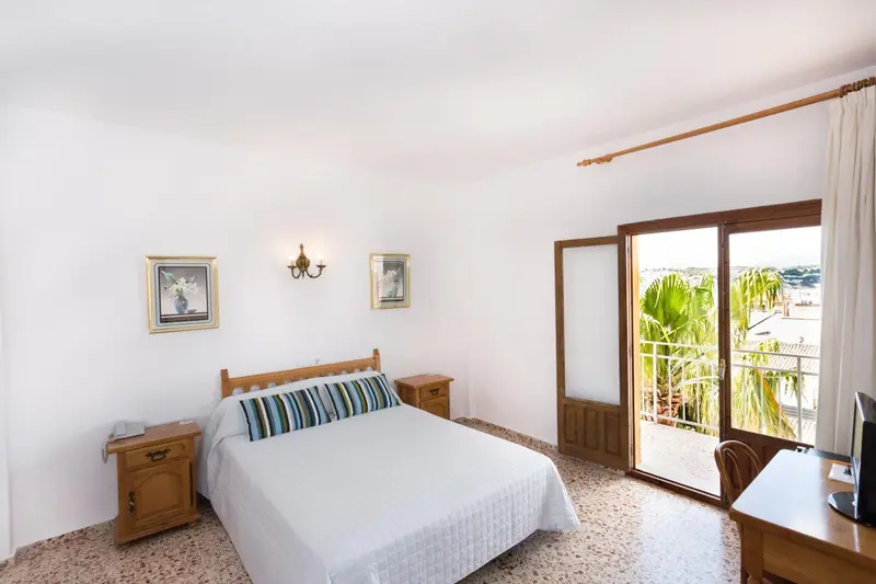 Une chambre lumineuse avec un lit double et un accès à une terrasse.