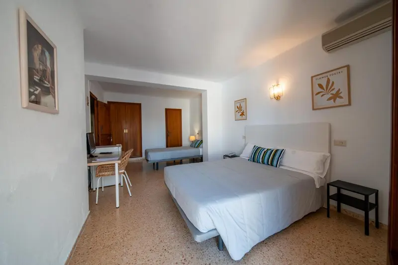 Une chambre lumineuse avec un grand lit et un bureau.