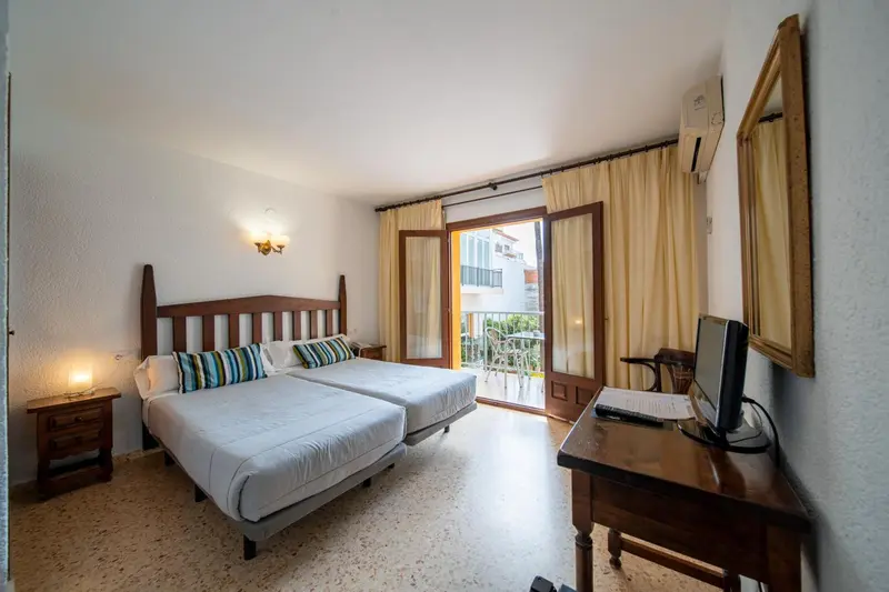 Une chambre lumineuse avec deux lits et un accès à un balcon.