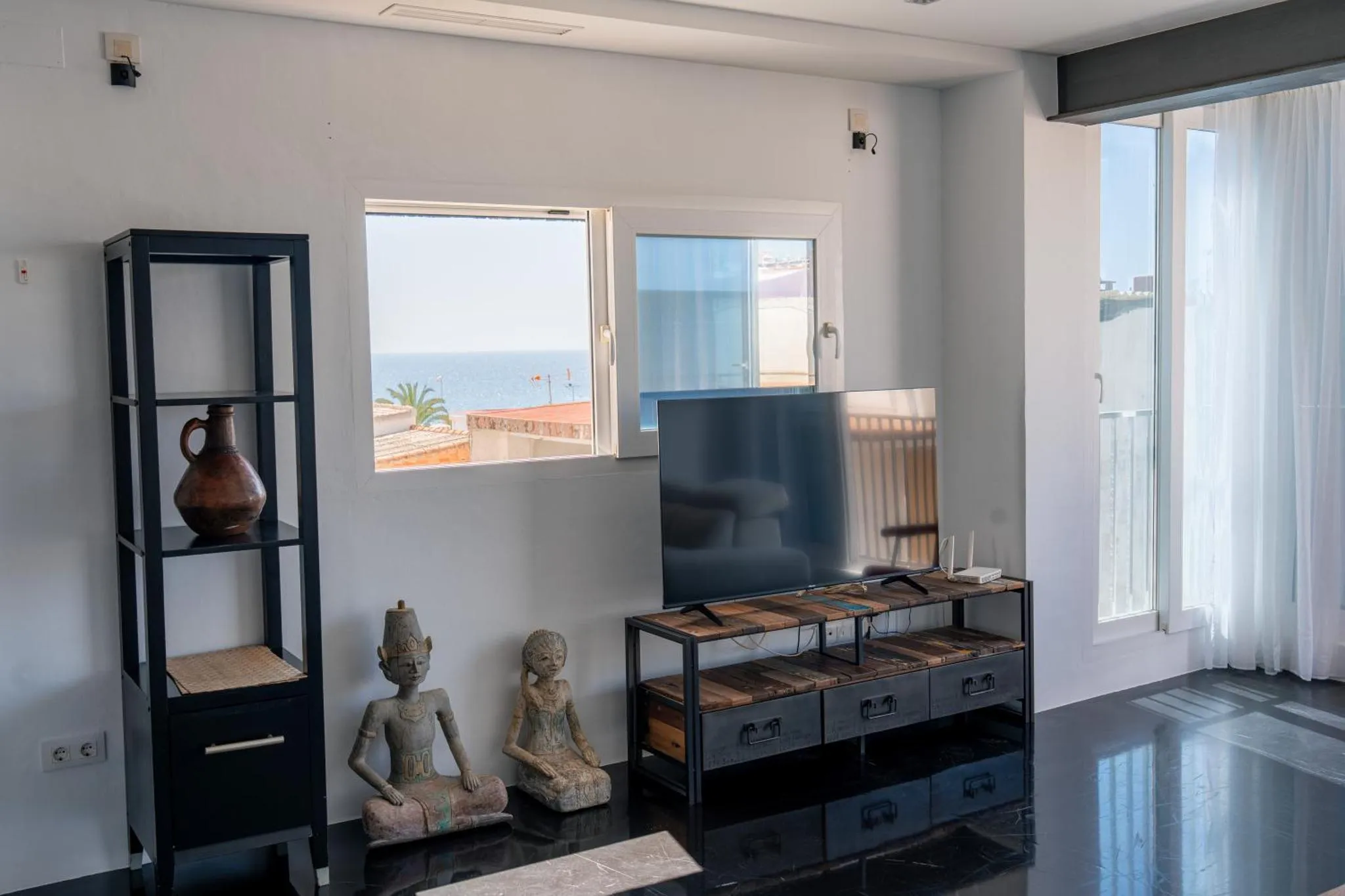 Espace de vie intérieur lumineux avec une décoration sobre et un accès à une vue sur la mer.