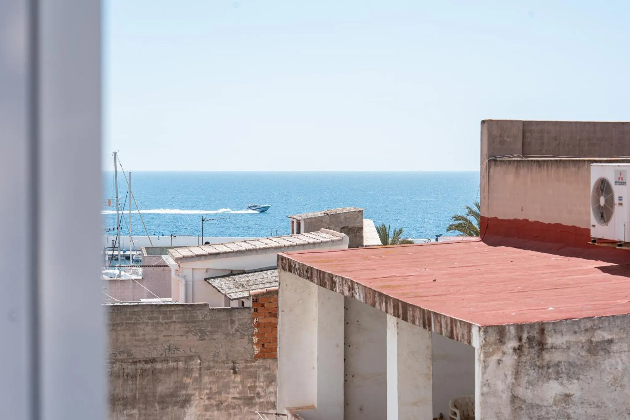 Vue sur la mer depuis un toit avec des unités de climatisation.