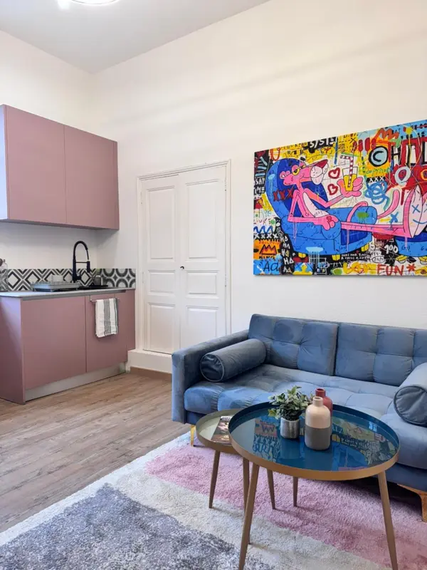 Un espace de vie lumineux avec un canapé bleu et une cuisine équipée.