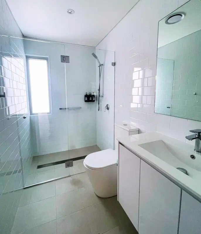Une douche à l'italienne moderne avec des carreaux blancs et un éclairage intégré.