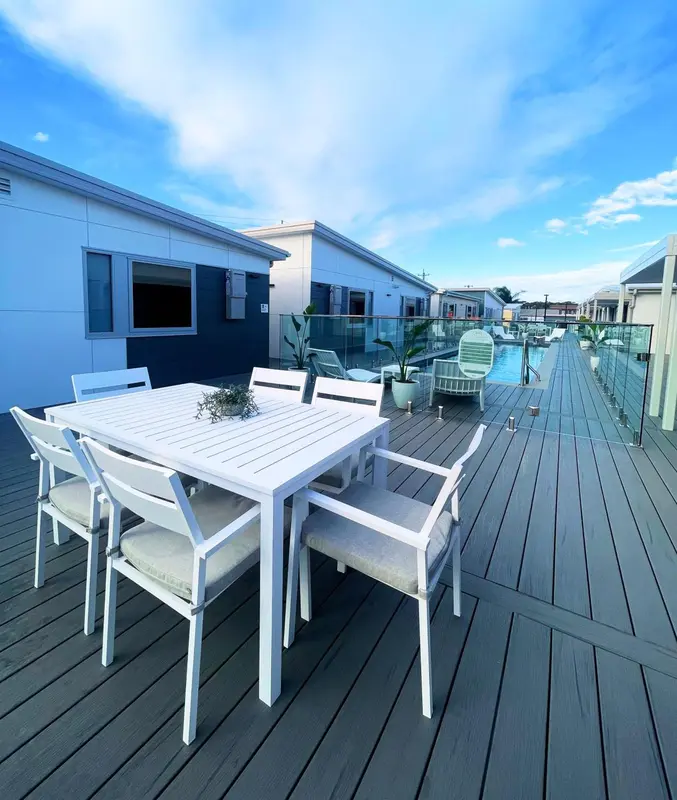 Terrasse aménagée avec table et chaises, devant des bâtiments modernes.
