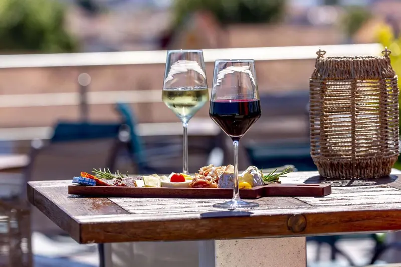 Deux verres de vin accompagnent une assiette de charcuterie et de fromages sur une table en bois.