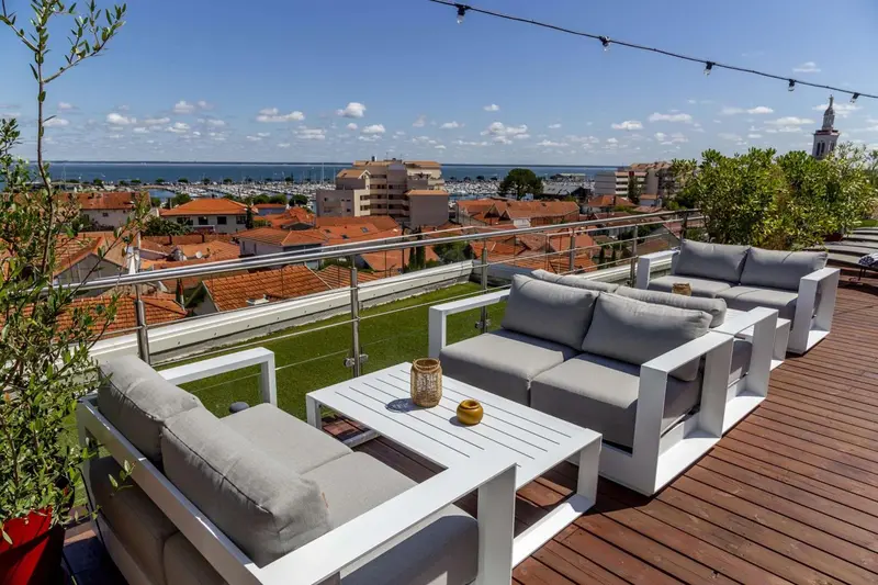 Terrasse aménagée avec des canapés et une vue sur la ville et la mer.