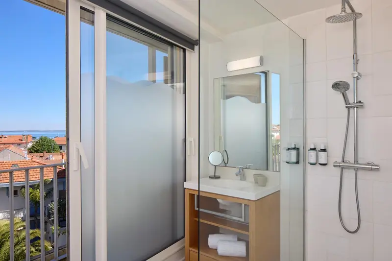 Une salle de bain lumineuse avec douche à l'italienne et vue sur la mer.