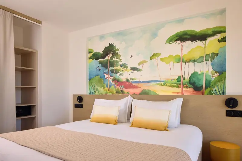 Une chambre lumineuse avec un grand lit et une décoration murale colorée.