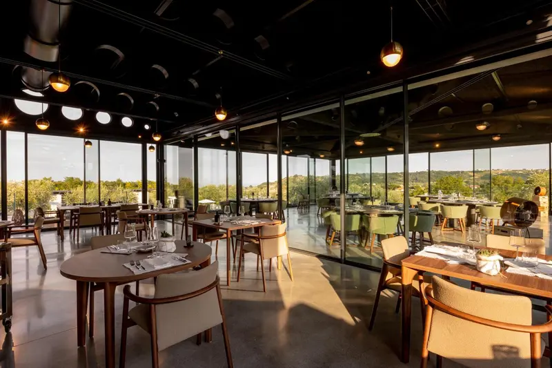 Une salle lumineuse avec de grandes baies vitrées donnant sur un paysage verdoyant.