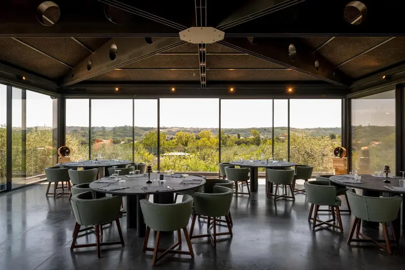 Une salle à manger lumineuse offre une vue dégagée sur un paysage verdoyant.