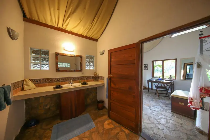 Une salle de bain ouverte sur une chambre avec un lit à moustiquaire.