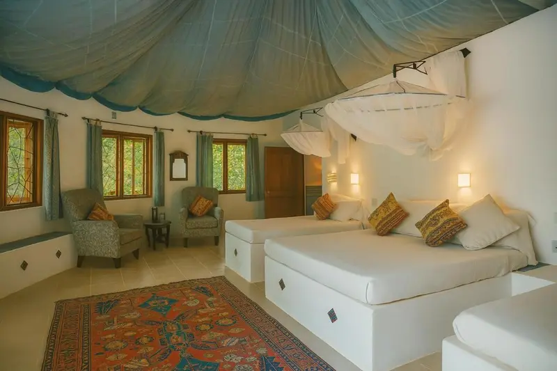 Une chambre lumineuse avec deux lits simples et un coin salon.