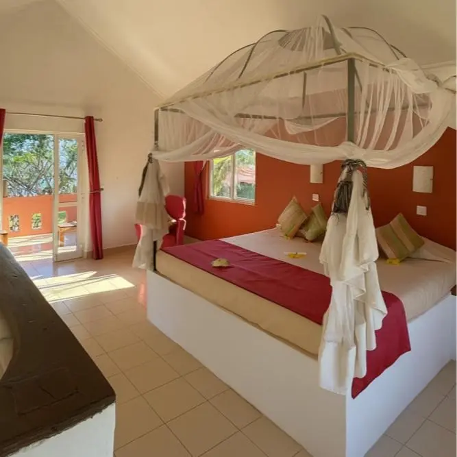Une chambre lumineuse avec un lit à baldaquin et une vue sur l'extérieur.