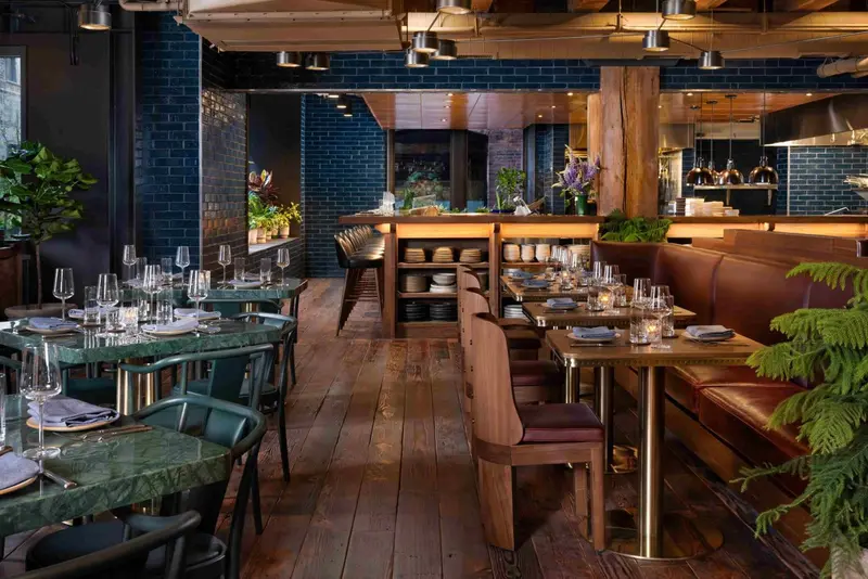 Une salle de restaurant lumineuse avec des tables dressées et des banquettes en cuir.