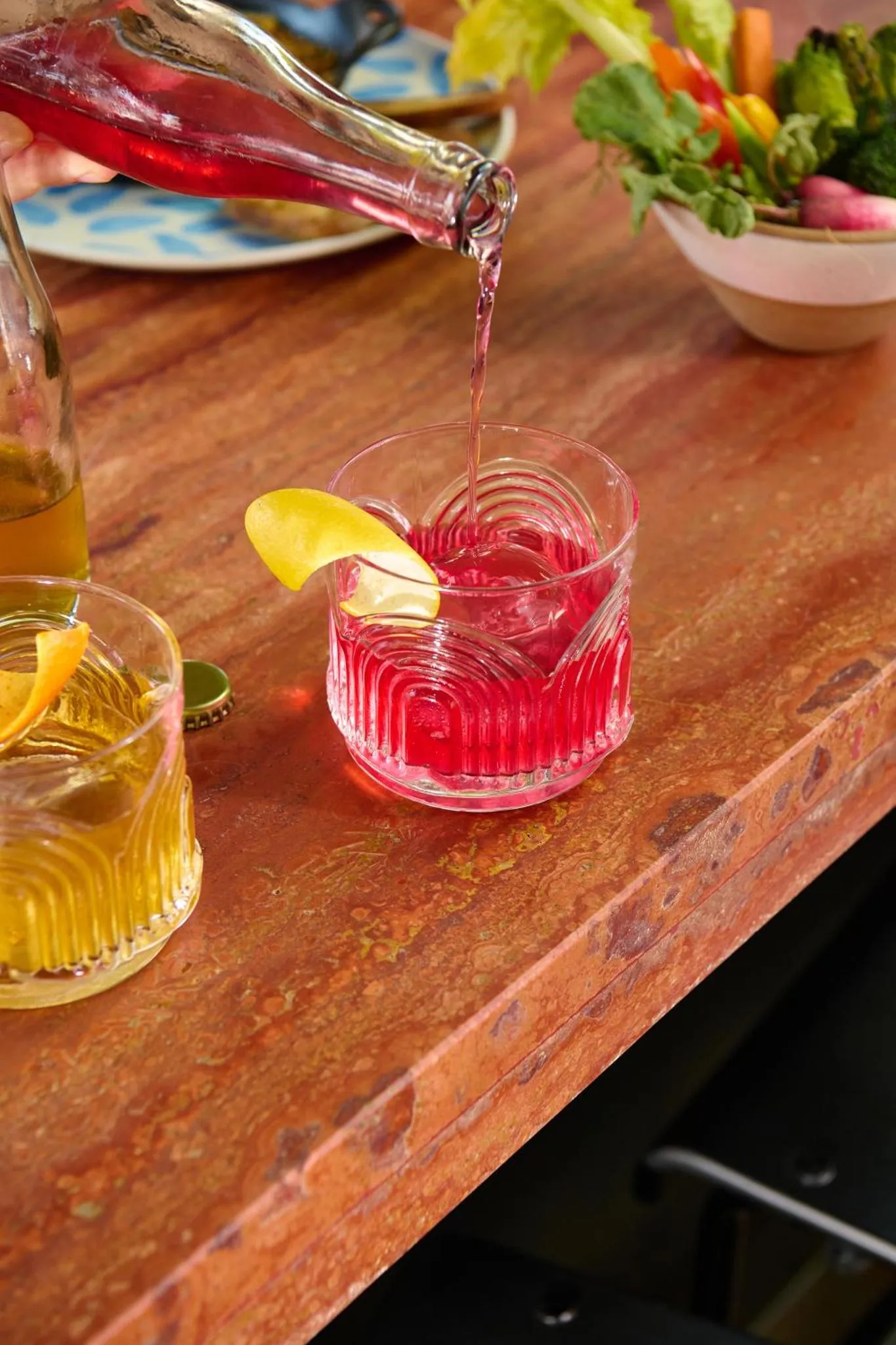 Une boisson rose est versée dans un verre décoré d'une tranche de citron.