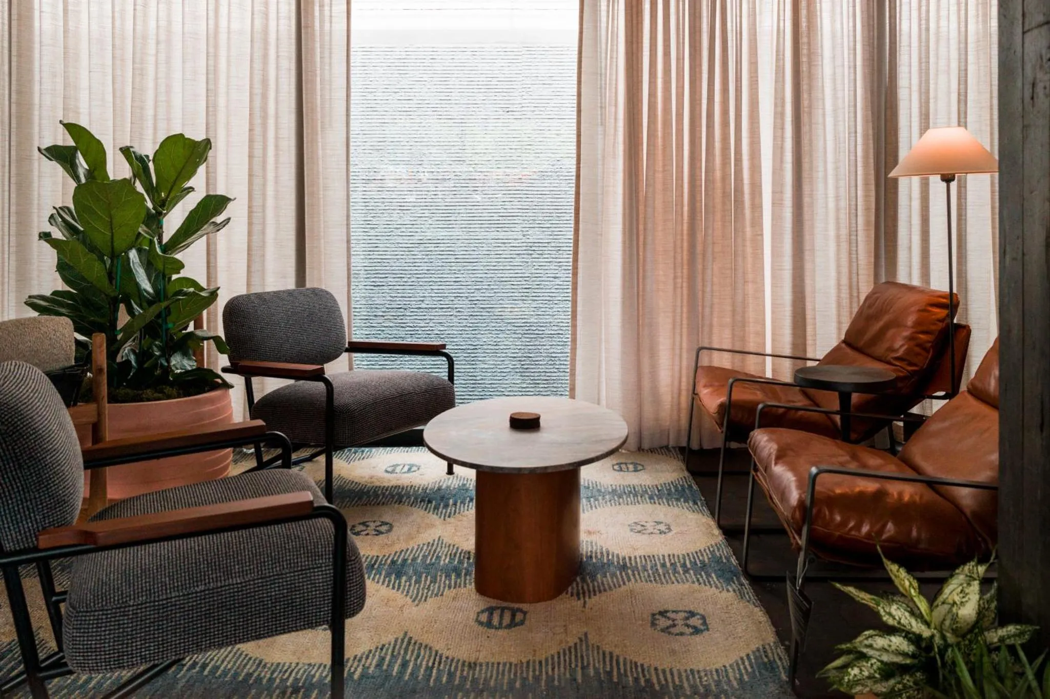 Un espace de détente avec des fauteuils et une table basse devant des rideaux.