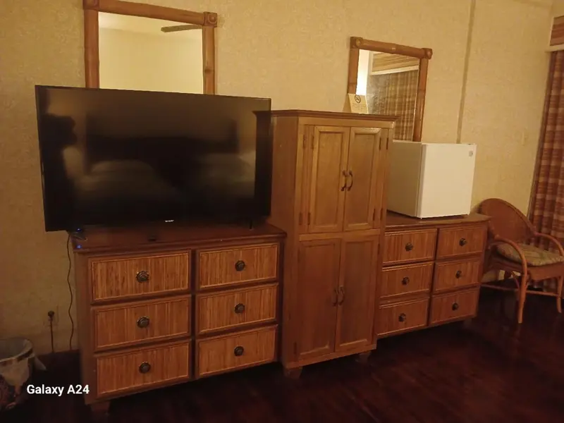 Une télévision est posée sur une commode en bois dans une chambre.