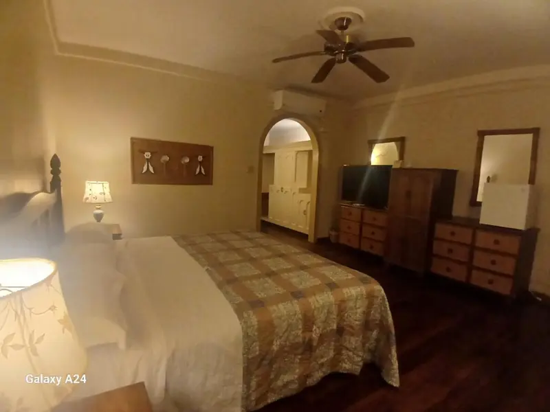 Une chambre lumineuse avec un grand lit et un meuble télévision.