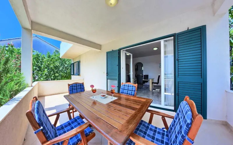 Une table et des chaises sont disposées sur une terrasse ombragée.