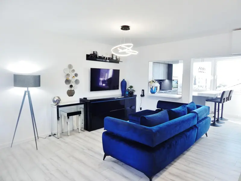 Un salon moderne avec un canapé bleu et un grand écran plat.