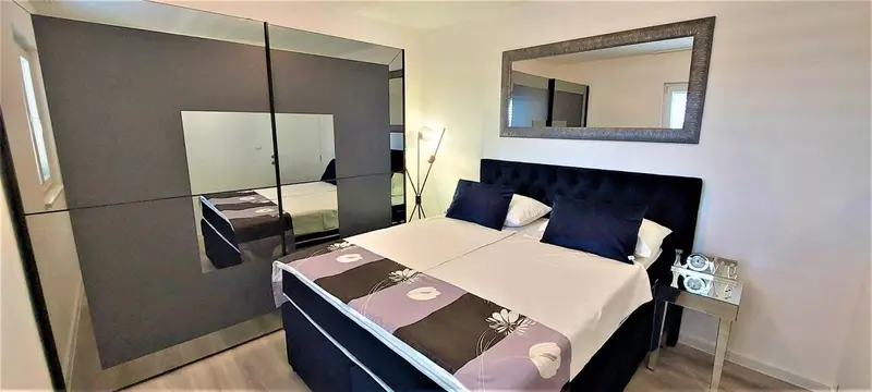 Une chambre moderne avec un grand lit et un dressing miroir.