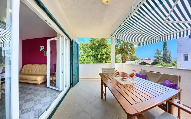 Une table est dressée sur une terrasse ombragée avec vue sur la végétation.