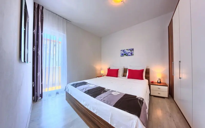 Une chambre lumineuse avec un grand lit et un accès à un balcon.