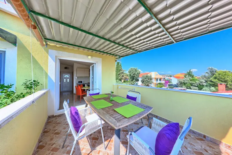 Une table à manger est mise en scène sur une terrasse ensoleillée.