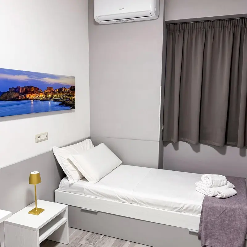Une chambre lumineuse avec un lit simple et une décoration sobre.
