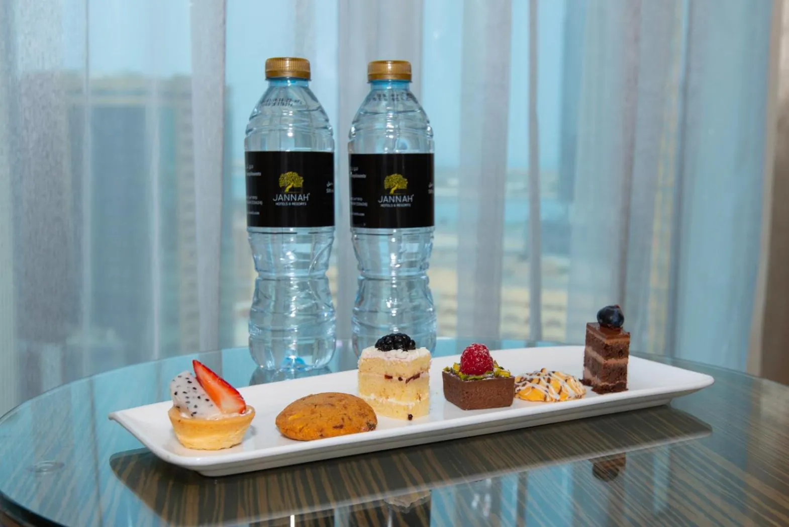 Assortiment de pâtisseries et bouteilles d'eau sur une table ronde.