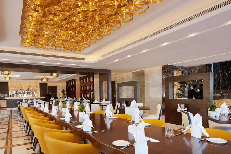 Une salle lumineuse avec de longues tables dressées pour un repas.