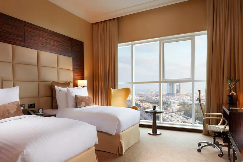 Une chambre d'hôtel lumineuse avec deux lits et une vue sur la ville.