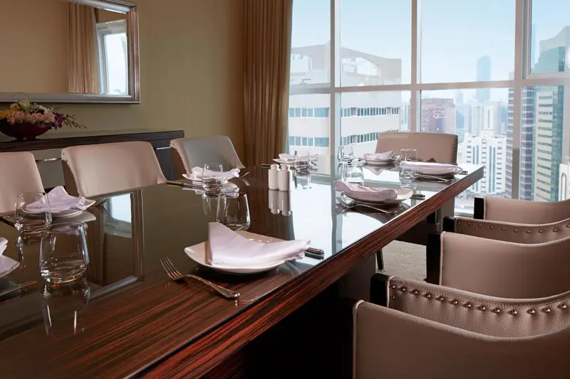 Une table à manger est dressée devant une grande fenêtre avec vue sur la ville.
