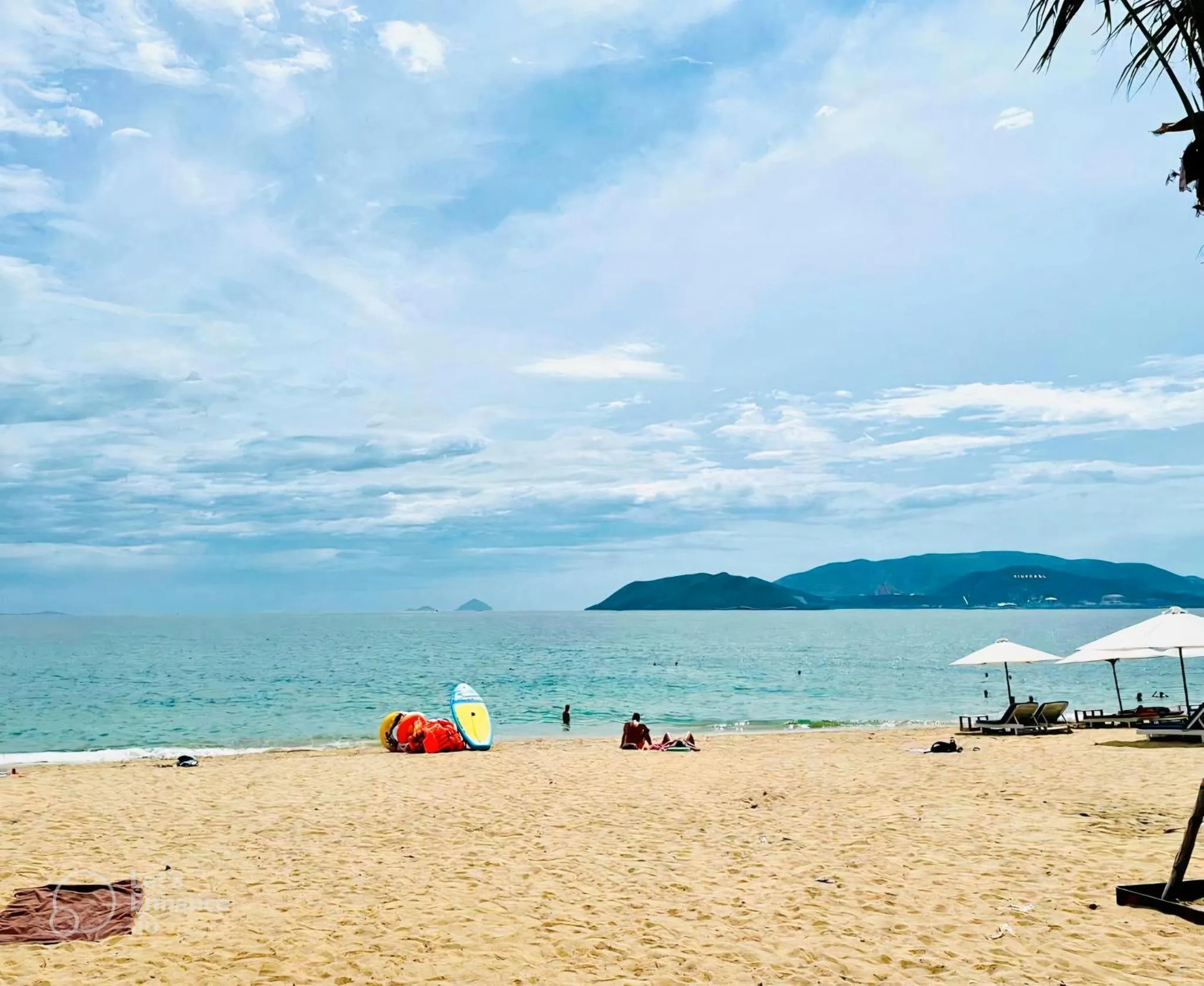Plage de sable fin avec parasols et quelques personnes.