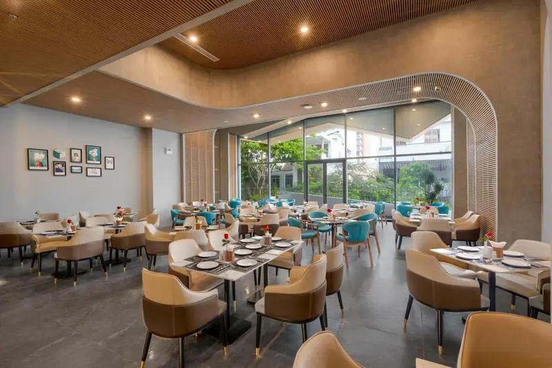 Une salle lumineuse avec des tables dressées pour un repas.