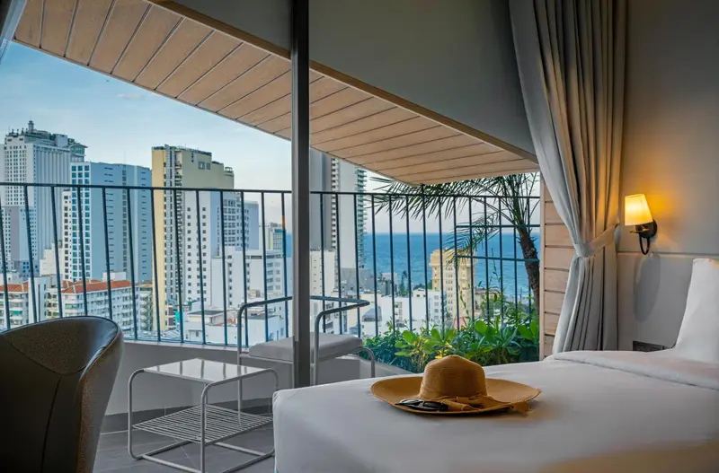 Une chambre d'hôtel avec un balcon donnant sur la mer et la ville.