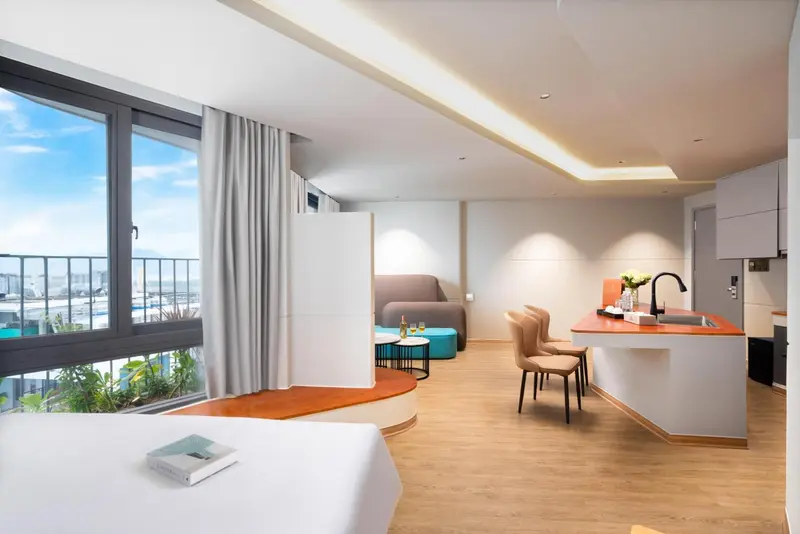 Une chambre lumineuse avec un coin salon et une kitchenette donnant sur une vue dégagée.