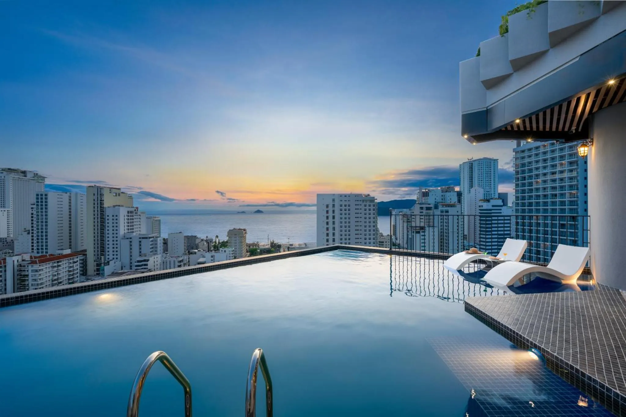 Piscine à débordement avec vue sur la ville et le coucher de soleil.