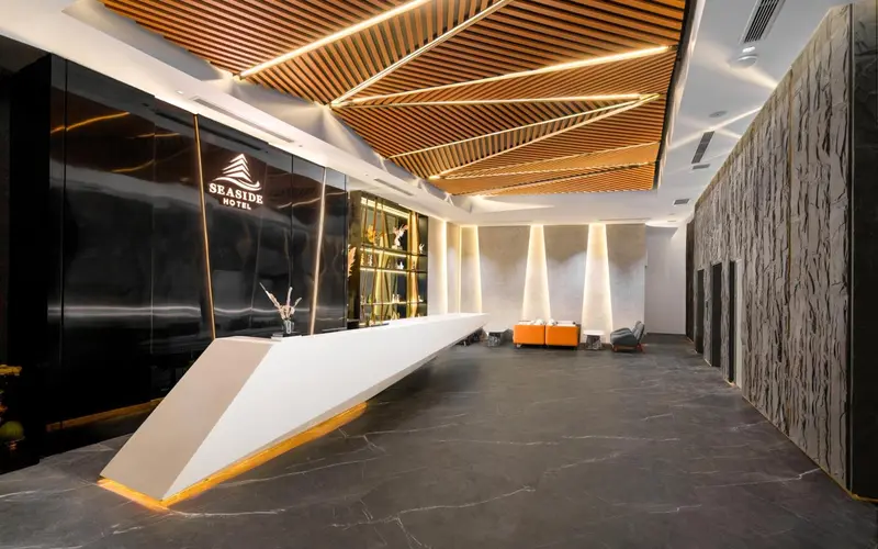 Hall d'accueil moderne avec comptoir blanc et murs texturés.